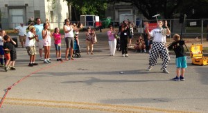 Dave Aiken also known as Checkerboard Guy entertains the crowd with his comedic juggling and antics as he teaches 8-year-old Rogen Henderson to balance a plate on a stick. Aiken is performing alongside buskers Bobby Maverick and Mama Lou at the Art City Austin Festival on April 12.